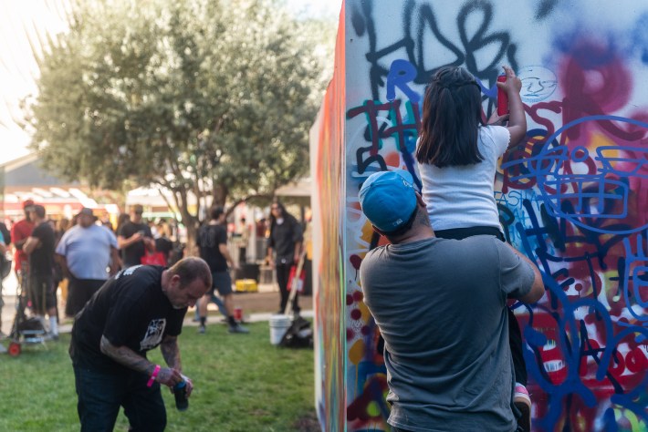 a dad holds his daughter up to paint