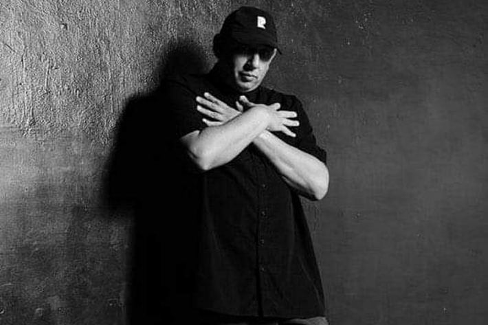 a black and white photo of a man in a cap with his arms across his chest