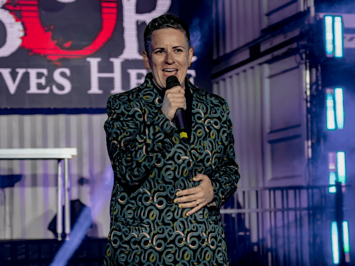 a woman in a suit patterned with snakes speaking into a microphone