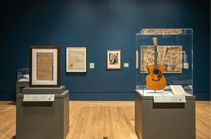 A "Declaration of Independence" copy on view next to a guitar owned and inscribed by Woody Guthrie