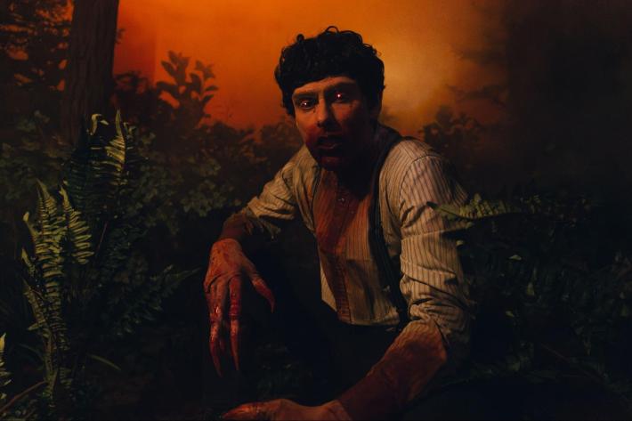 a scareactor dressed as a vampire with glowing eyes