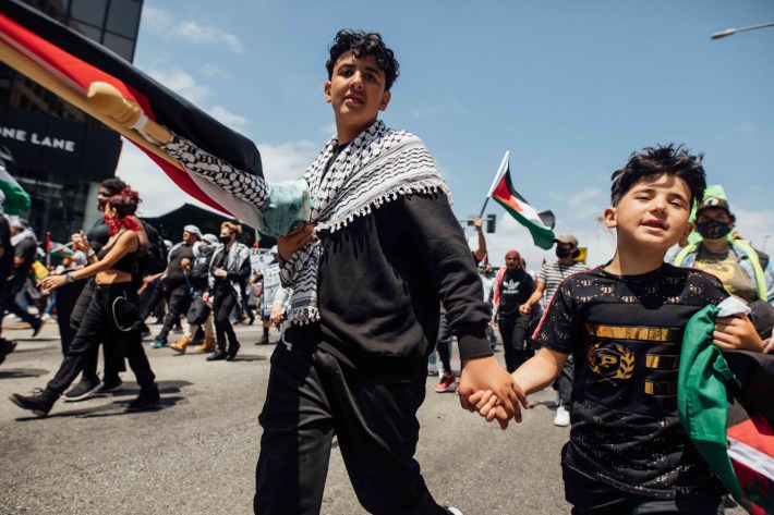 Two young protestors hold hands as they march.