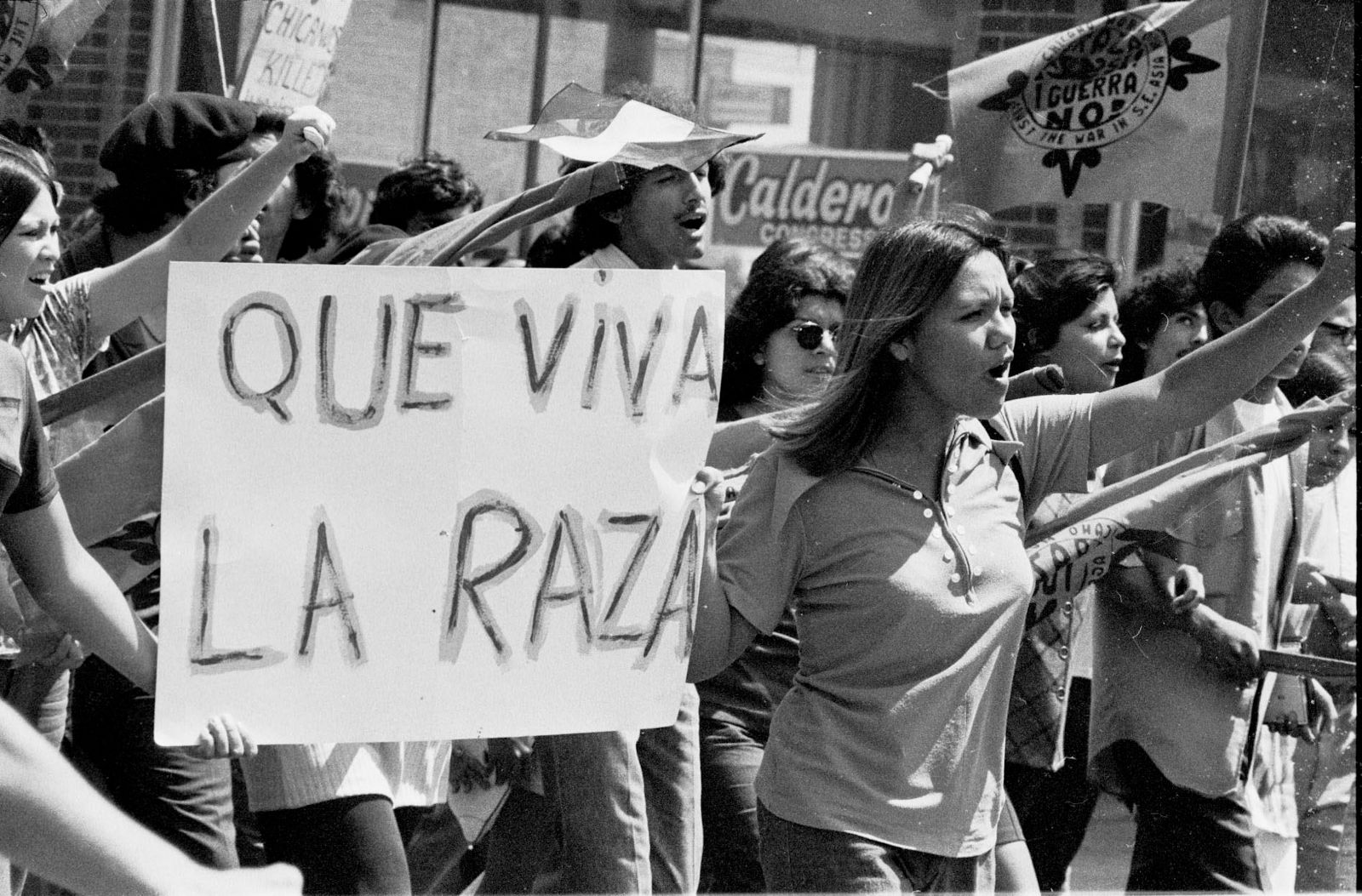 Women in Chicago protesting in 1970 with raised fists, with a sign that says "Que Viva la Raza"