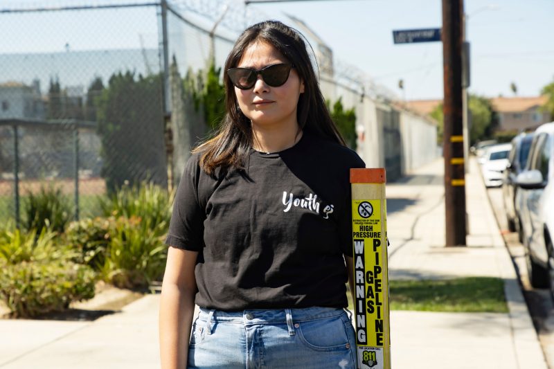 Ashley Hernandez stands near an oil drilling site in Wilmington, a neighborhood in south Los Angeles County, California. Photo by Ted Soqui.