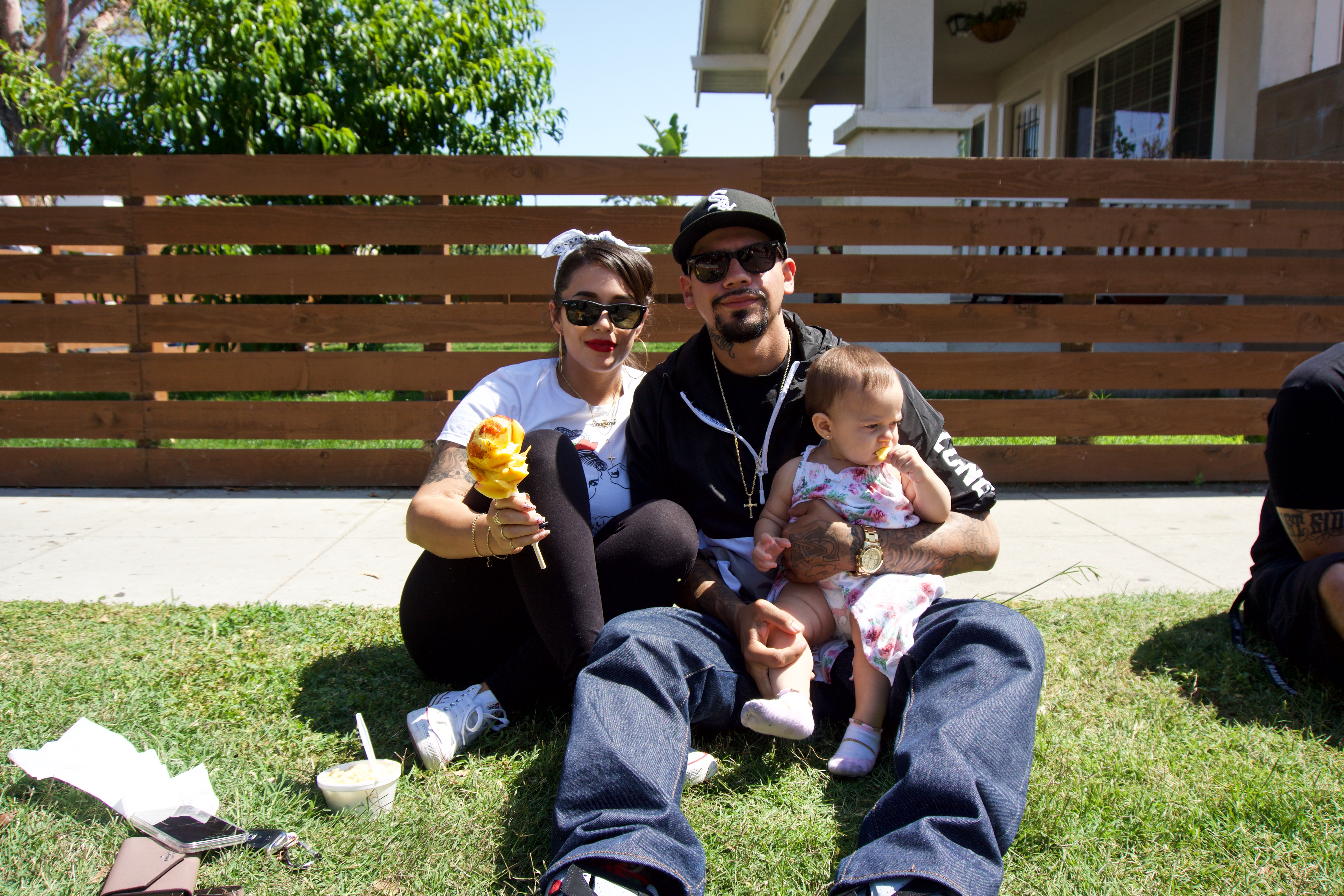 A local family enjoys a spiralized mango on a stick, a popular street vendor treat during the summer months.