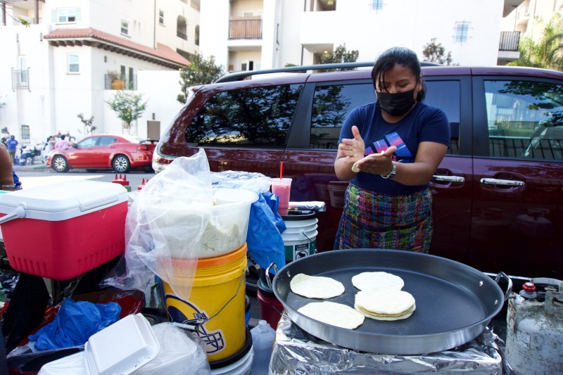 A street vendor makes tortillas by hand.