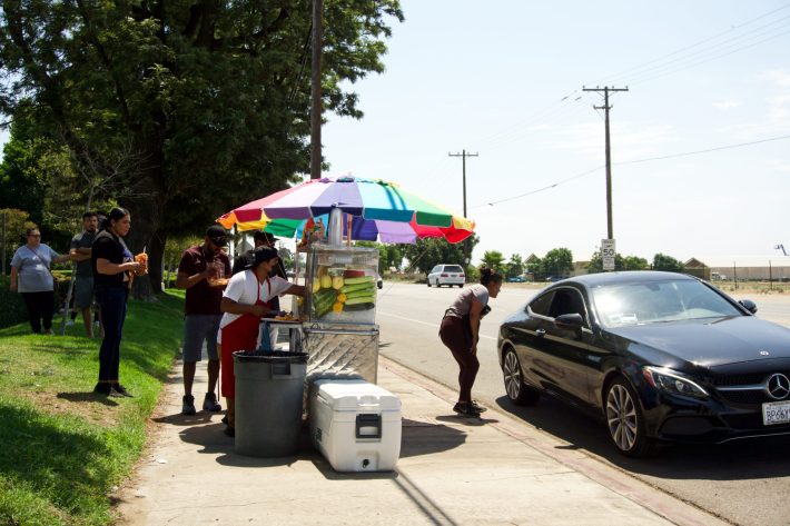 Jose Luis Ramirez talks with a customer who stopped by to donate money and give her condolences to the vendors.