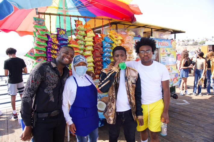 High Off Energy members pose with one of the many street vendors who operate alongside Santa Monica Pier. Anytime they perform near vendors the three friends will buy drinks and snacks from any vendor who's around them.