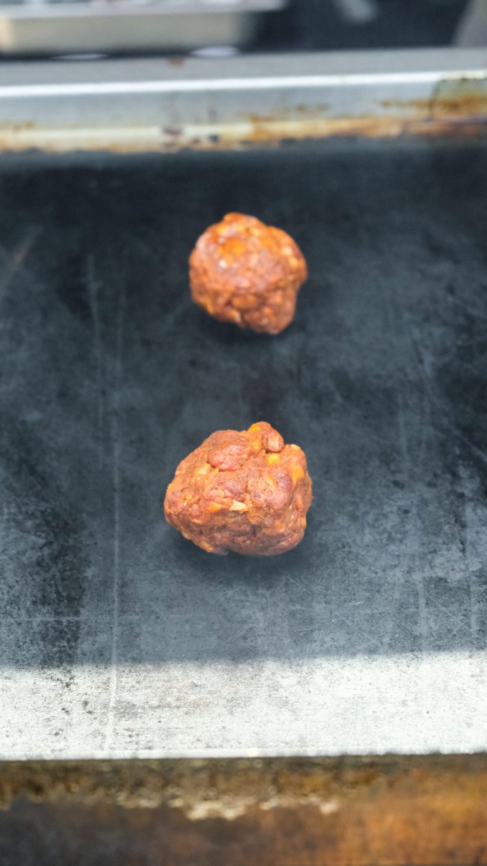 Balls of birria seasoned beef on the grill.