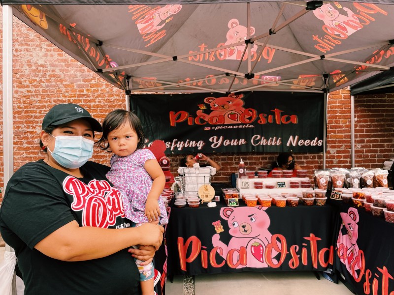 Yasmin Alvarez of Pica Osita poses with her daughter in front of her stand. The mother of two runs a candy stand where she sells sweet and spicy candy and rim dips.