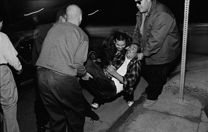 A Clarence Gang member is hit with five bullets from an automatic weapon on the night of a gang truce in East Los Angeles. His fellow gang members rush him to the hospital. Boyle Heights, Los Angeles, CA, 1993