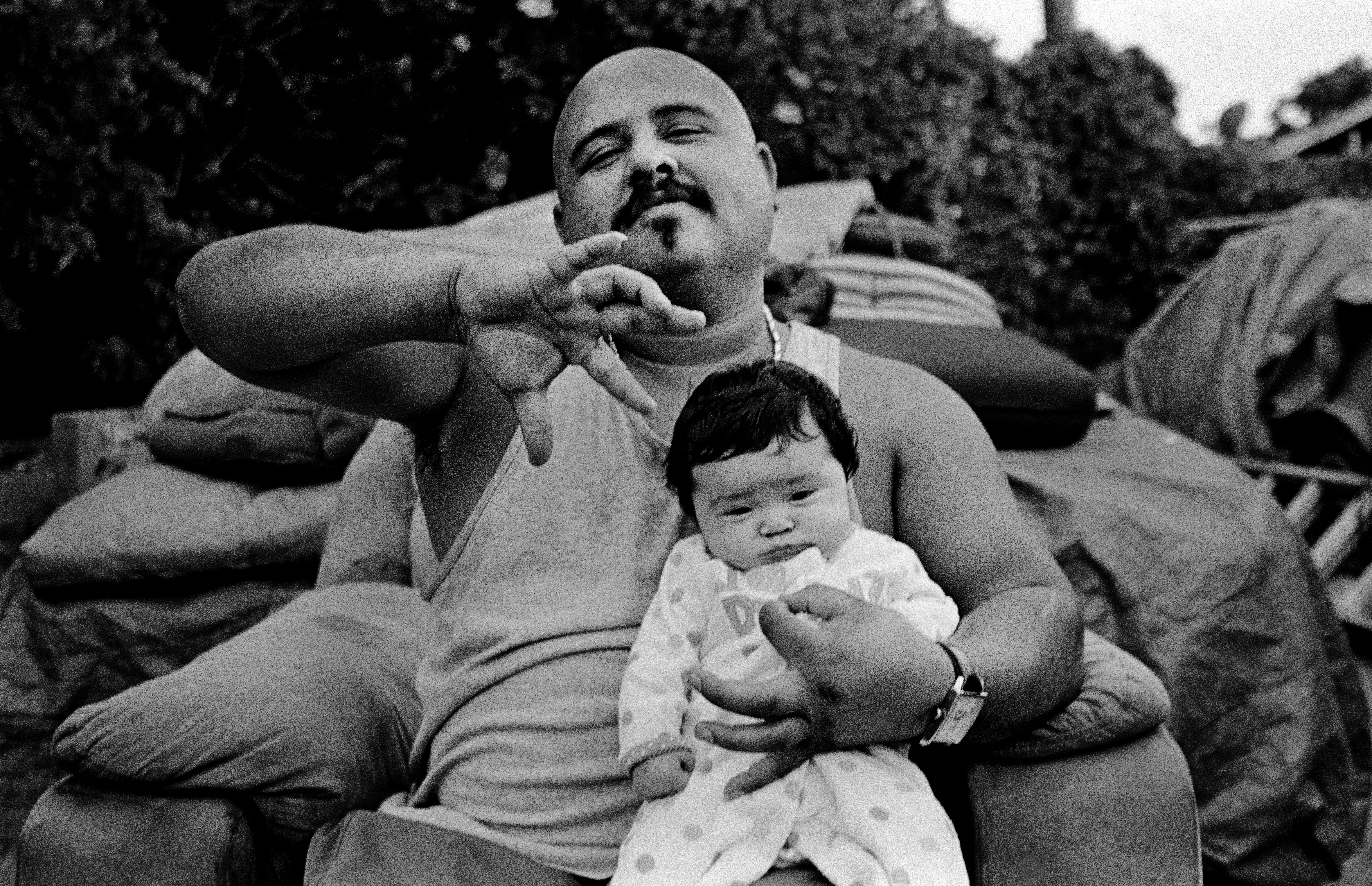 Igor showing gang signs while holding his daughter.