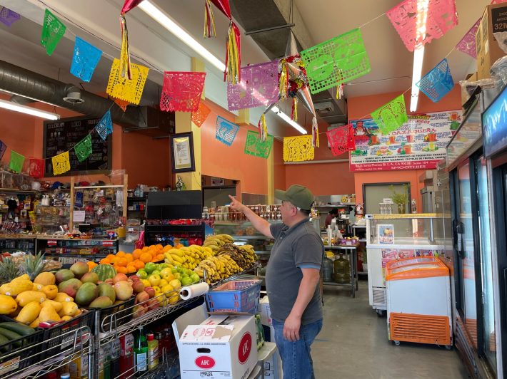 Man shows around his neighborhood market.