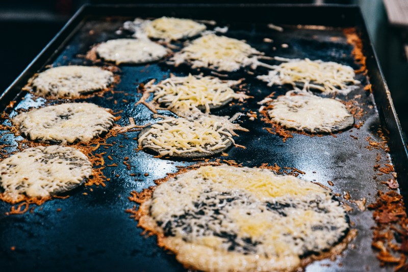 Blue corn tortillas covered in cheese cooking on the plancha.