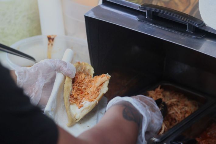 Stuffing a fried quesadilla with tinga de pollo.